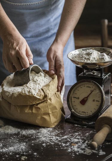 Baker weighing flour on a scale.