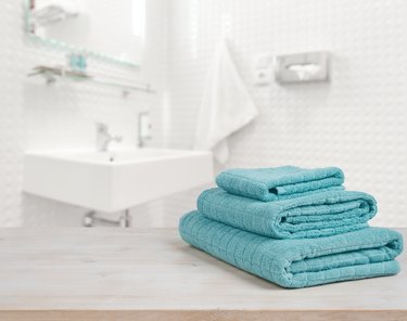 Turquoise spa towels pile on wood over blurred bathroom background