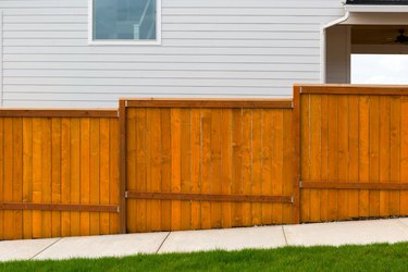 New home backyard red stained cedar wood fence construction