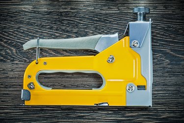 Building stapler gun on wooden board