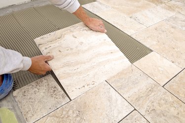 Worker Places New Marble Tile on a Bathroom Floor