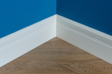 Moulding in the corner. Blue Matte Wall with laminate immitating oak texture