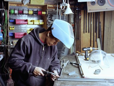 Young workman welding joint on metal frame