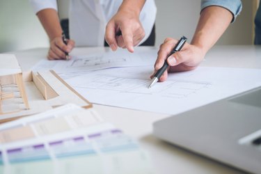 Midsection Of Engineers Making Blueprint At Desk