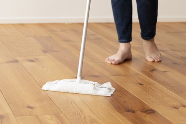 Feet of young woman mopping the floor of wood