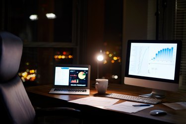 Laptop and computer on office desk at night