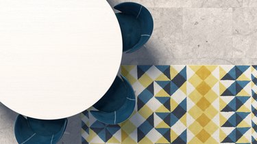 Empty white tabletop with blue armchair standing on the concrete floor with geometric patterned carpet