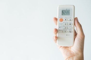 Woman hand using remote control open air conditioning 25 degrees. Open air 25 degrees, is temperature, save energy