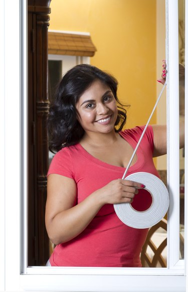 Energy Efficiency Hispanic Woman Applies Weather Stripping Vertical