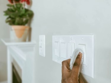 Woman Cleans Light Switches Using Disinfectant Wipe
