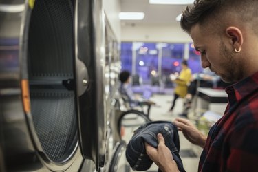 Young man checking stain on jeans at laundromat