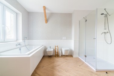 Bathtub and glass shower cabin in loft bathroom.