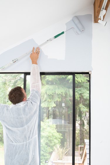 Man painting interior of home with roller
