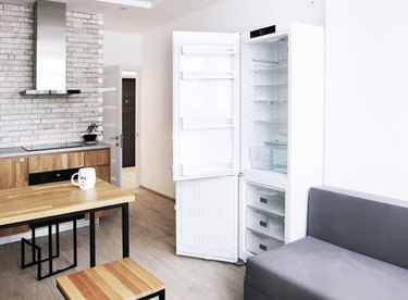 Scandinavian kitchen design with open fridge and sofa, oak furniture, horizontal