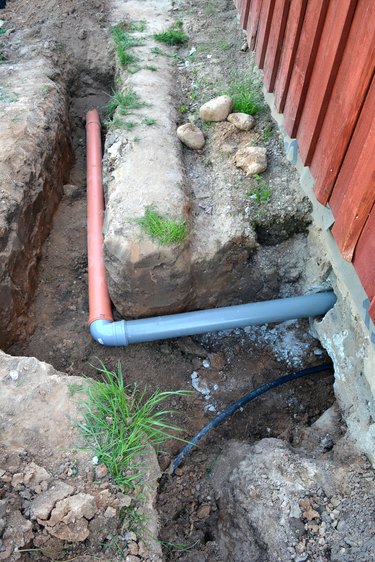 Trench near house with water and sewerage pipes