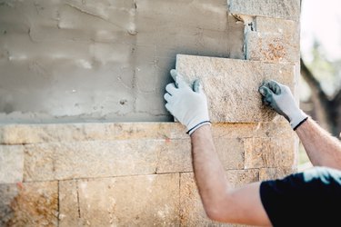 Construction worker installing stone on architectural facade of new building. details of construction industry