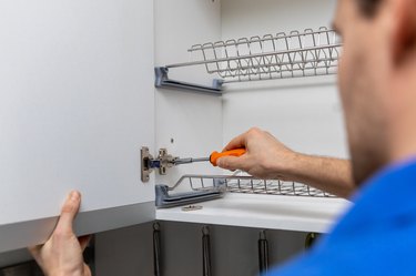 handyman doing kitchen cabinet hinge adjustment