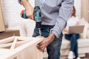 Man handyman is engaged in assembly of furniture. Repairman is engaged in repairing furniture.