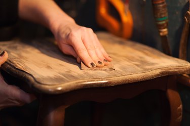 Close-up of woman sanding table top.