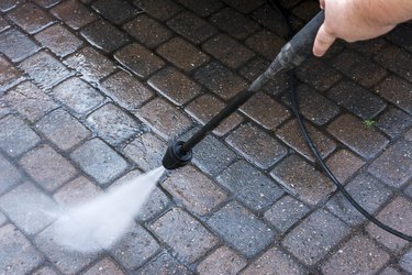 Guy using a pressure washer on courtyard with paving stone