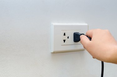 Cropped Hand Of Woman Touching Electric Plug