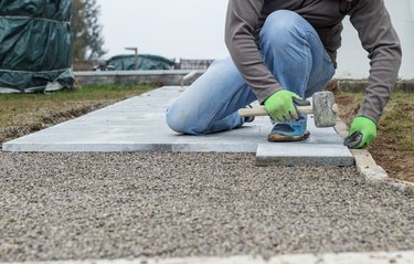 worker hammering the stone plates to install footpath at garden