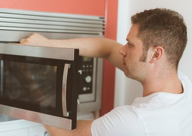 Male technician repairing microwave oven.
