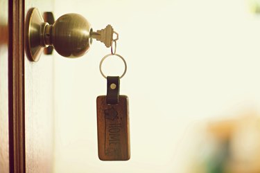 House key with home keyring in keyhole, property concept