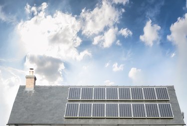 Solar Panels On The Roof Of A House Under A Bright Sky