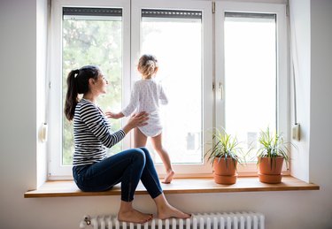 Mother with her little daughter looking out of window