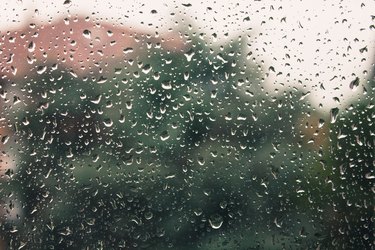 Blurry house and trees silhouette seen through a wet window