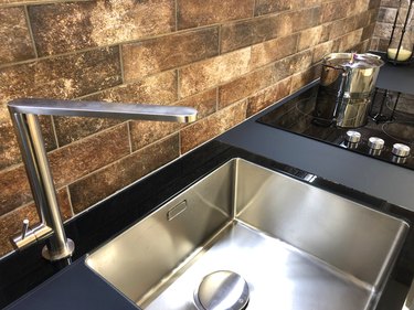 Image of rectangular kitchen butler sink, white stainless stee sink with black granite worktop countertop and composite modern induction ceramic hob / black kitchen cooker stove electric hot plate zones with touch control knobs