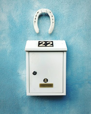 Close-Up Of Number On Mailbox Mounted Over Blue Wall With Horseshoe