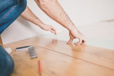 The hands of the master in the process of installing laminate