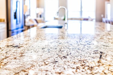 New modern faucet and kitchen room sink closeup with island and granite countertops in model house, home, apartment