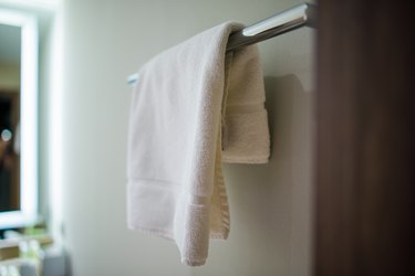 White Towel Hanging From Metal Rod In Bathroom