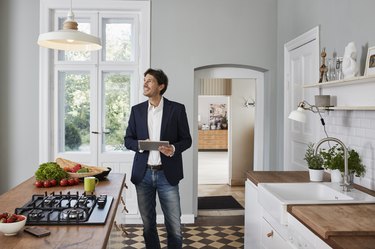 Man using tablet in kitchen looking at ceiling lamp