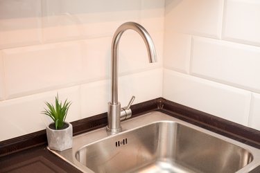 Modern kitchen with metal sink, white decorative wall