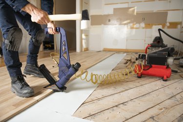 A Male Worker install wood floor on a house