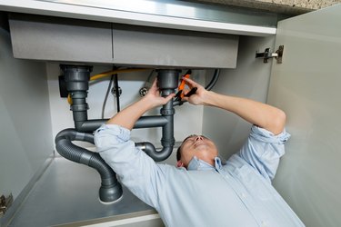 Man repairing sink pipe in the kitchen