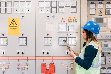 Young businesswoman standing in front of the control panel in the control room