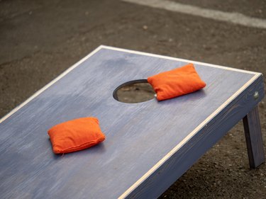 Orange beanbags sitting on blue cornhole board platform