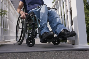 Man with spinal cord injury in a wheelchair on the top of home access ramp
