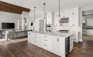 Beautiful kitchen in new luxury home with island, pendant lights, and hardwood floors. Features view of living room with vaulted ceiling.