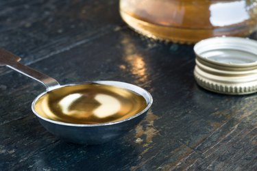 Close-Up Of White Wine Vinegar In Tablespoon On Wooden Table