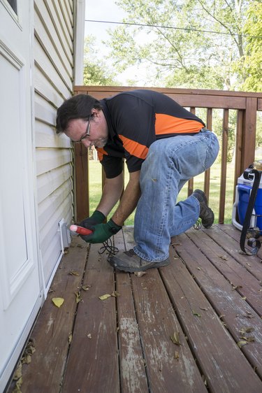 Electrician testing outside outlet on patio deck.