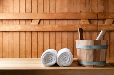 Wooden bucket and white rolled towels in a sauna