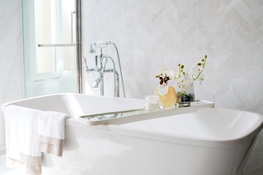 Closeup chrome faucet and showerhead, white bathtub.