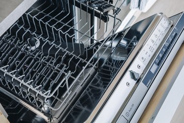Open empty dishwasher machine close-up in modern kitchen.