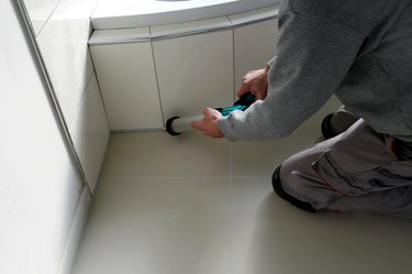 Man sealing a bath or basin with silicone